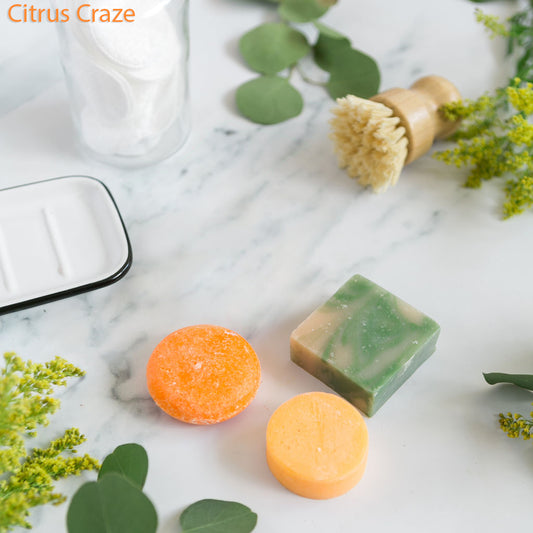 An assortment of solid shampoo, conditioner, and soap bars in various colors displayed on a marble surface.