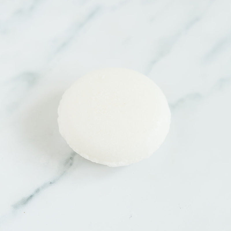 A white shampoo bar on a marbled counter top