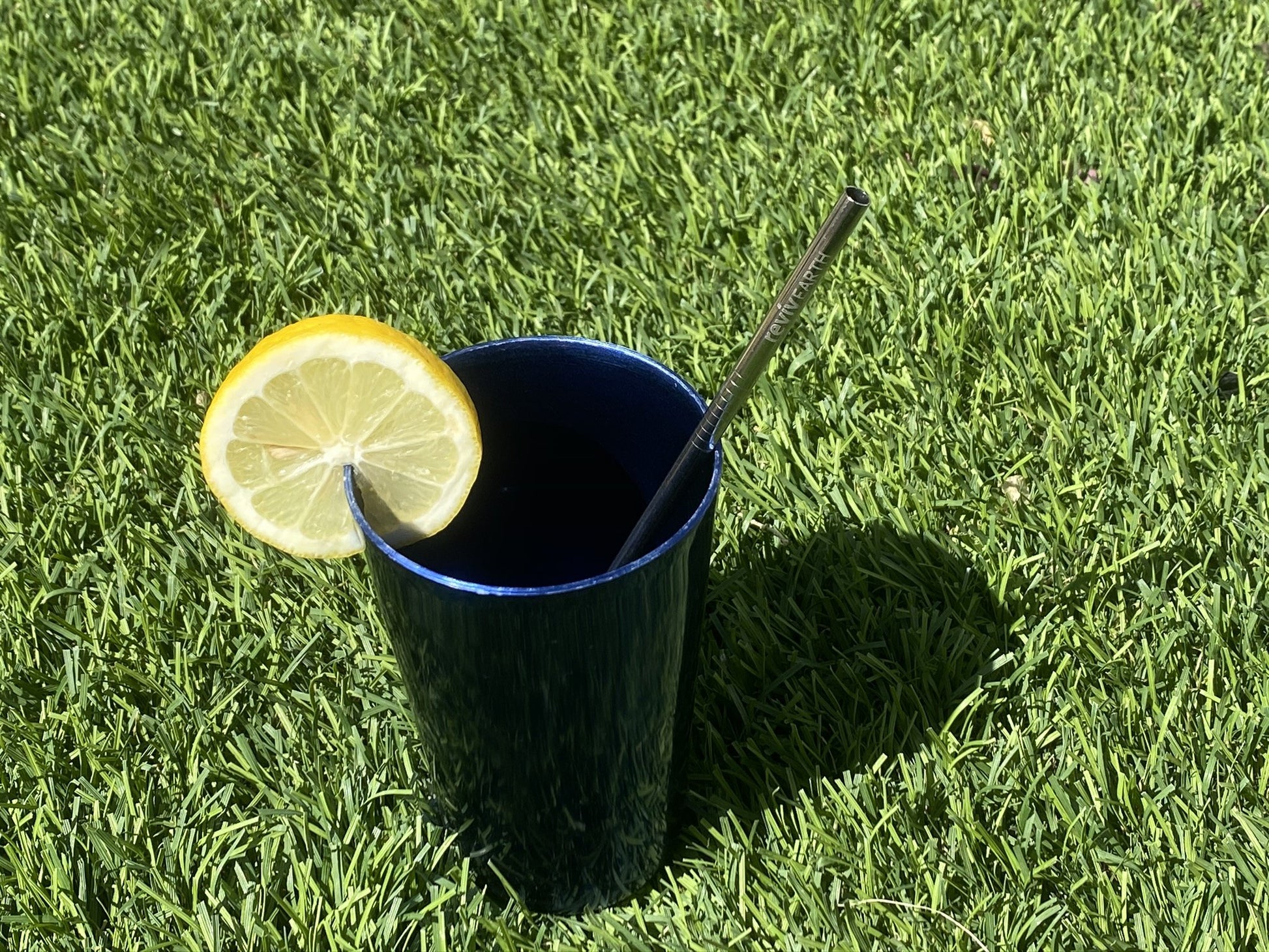 A straw stainless steel inside a black glass with a slice of lemon
